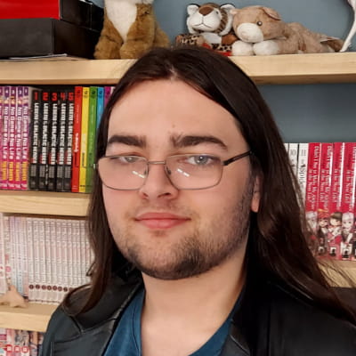 A photograph of James standing in front of a bookshelf filled with light novels.